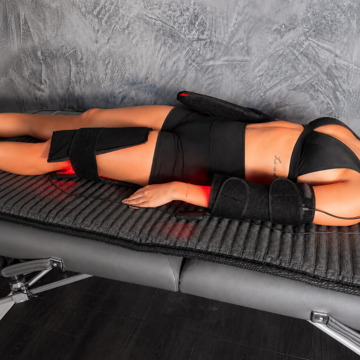 Person lying on a massage table with black massage gloves on hands and feet.